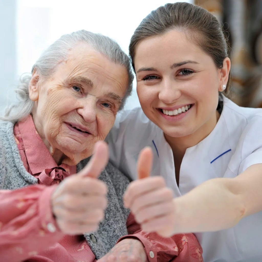 Carer and client smiling together, giving a thumbs-up